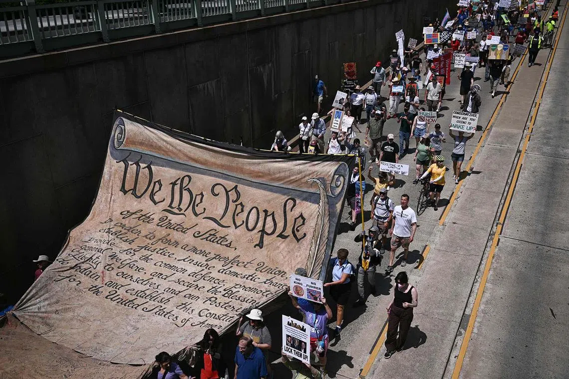 Protesters carry a replica of the Deceleration of Independence as they march through the city during a May Day Strong Coalition rally in Washington, DC on May 1, 2025. (Photo by Brendan SMIALOWSKI / AFP)