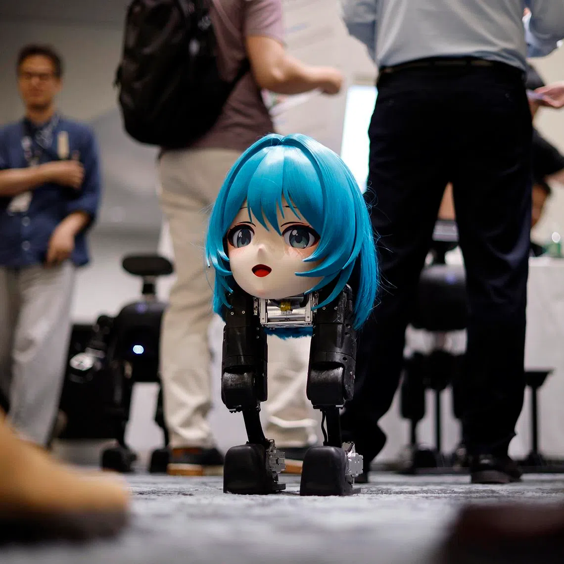 Bipedal robot ‘Mini Pi’ of Chinese robotics startup High Torque Technology stands surrounded by visitors during the Humanoids Summit in Tokyo on May 28.