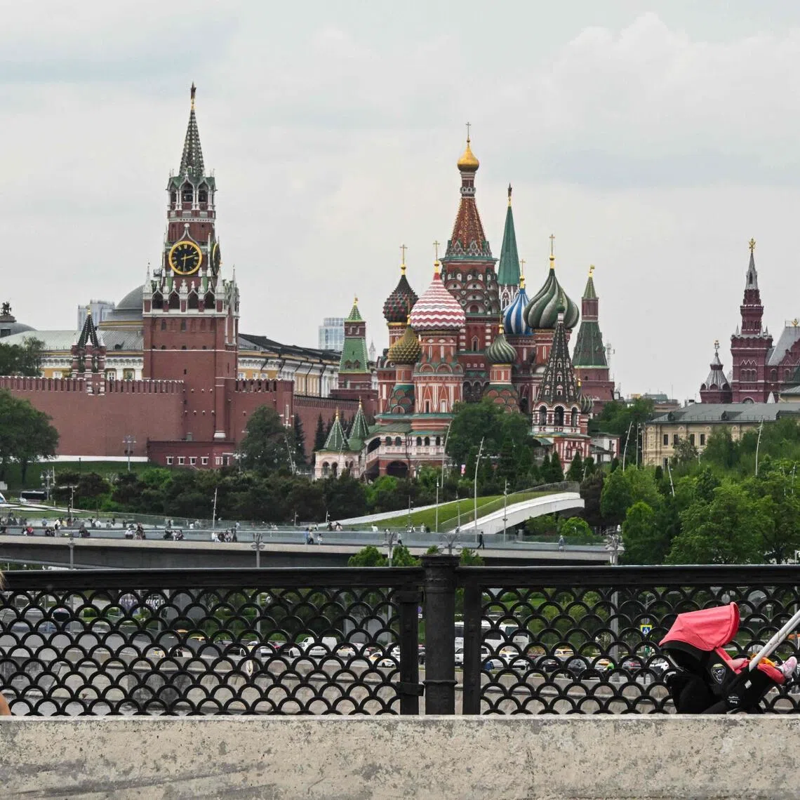 A family walks across Bolshoy Ustyinsky bridge, with Red Square in the background, in central Moscow on May 15, 2026. (Photo by Igor IVANKO / AFP)