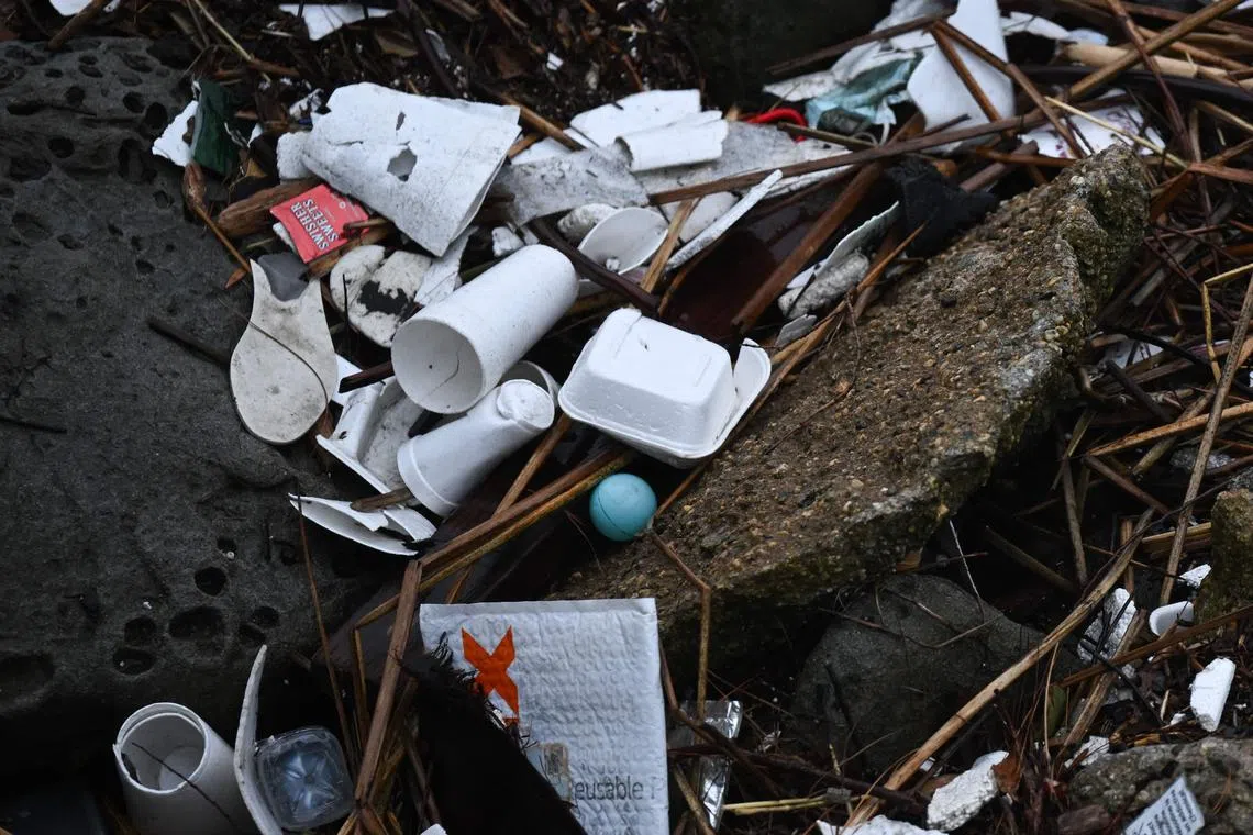 TOPSHOT - Plastic waste and foam food packaging rests on rocks as storm water runoff from a winter storm flows from Ballona Creek into the Pacific Ocean in Marina Del Rey community of unincorporated Los Angeles County, California, on March 14, 2023. (Photo by Patrick T. Fallon / AFP)