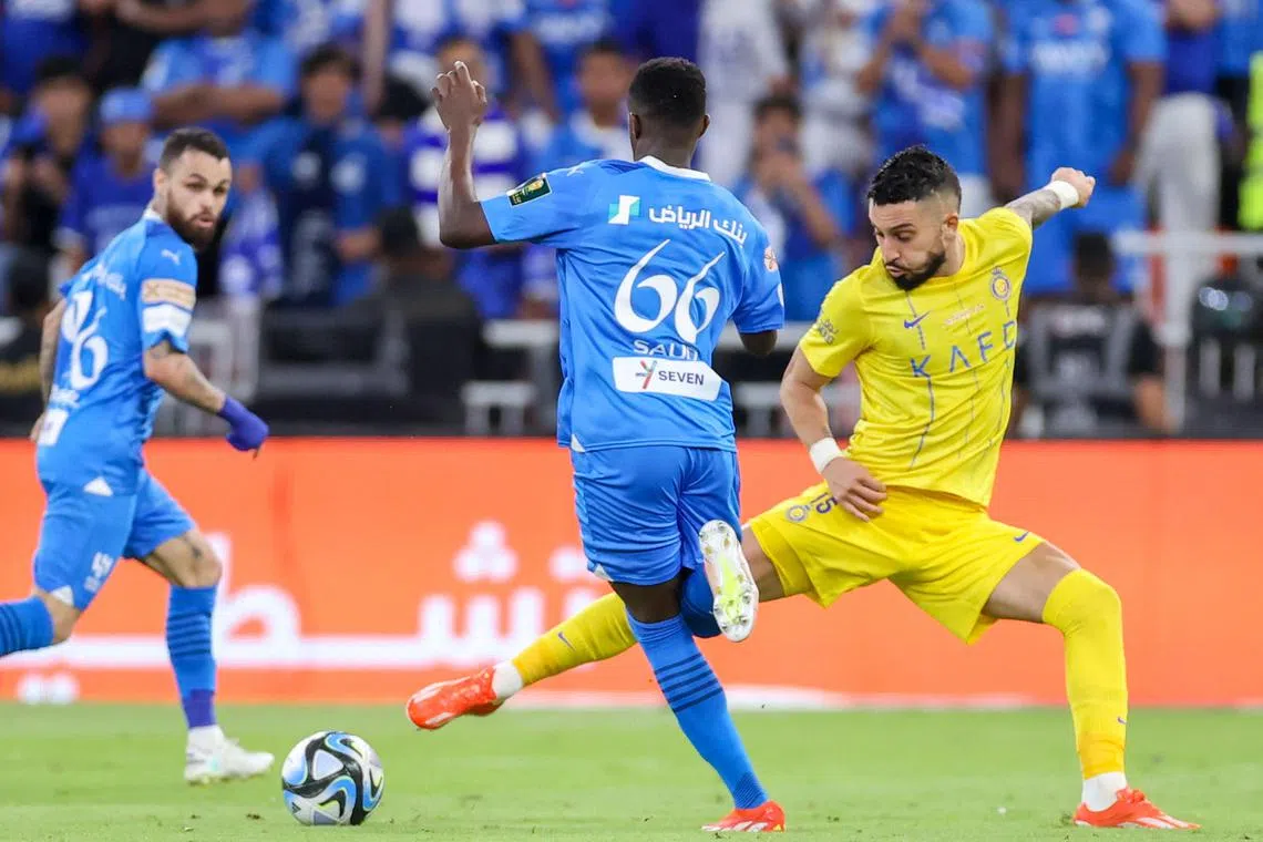 Al Hilal's Saudi defender Saud Abdulhamid (blue) is marked by Al Nassr's Brazilian defender Alex Telles in the King's Cup final at the King Abdullah Sport City Stadium in Jeddah on May 31, 2024.
