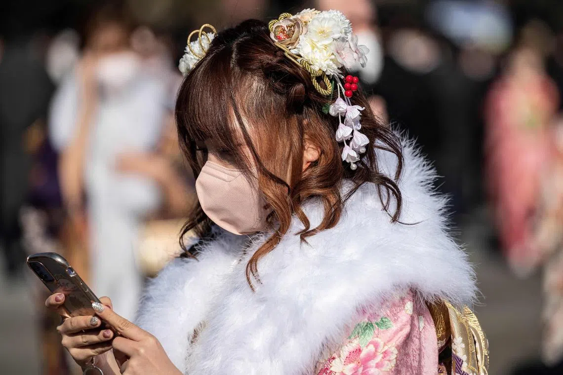 A young woman looks at her phone after attending a ceremony at theTodoroki Arena on Jan 9, 2023. 