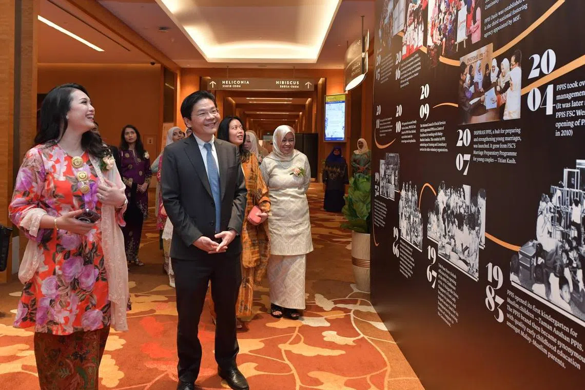 DPM Lawrence Wong touring an exhibition at the Singapore Muslim Women’s Association's (PPIS) 70th anniversary gala dinner with PPIS president Hazlina Abdul Halim.