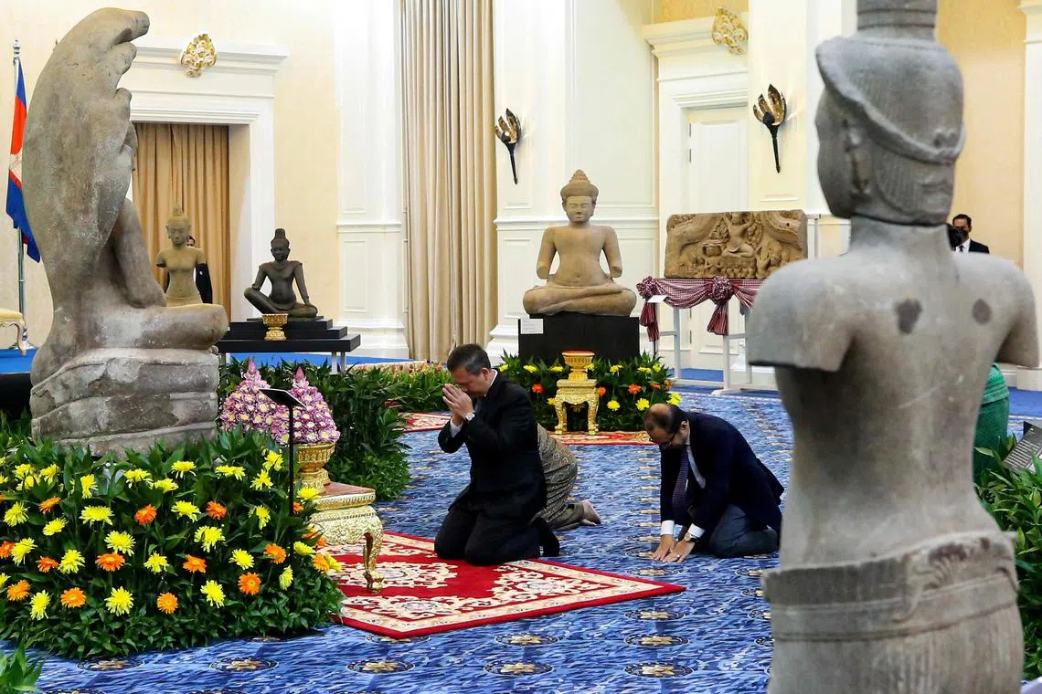 Cambodia's Prime Minister Hun Manet (centre) paying his respects in front of Khmer artefacts returned from the United States.