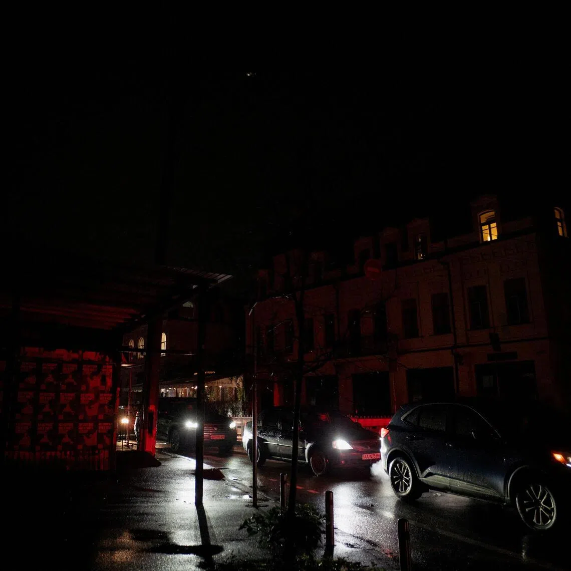 Commuters drive their vehicles on a non-illuminated street during blackout hours in Kyiv on Nov 21.