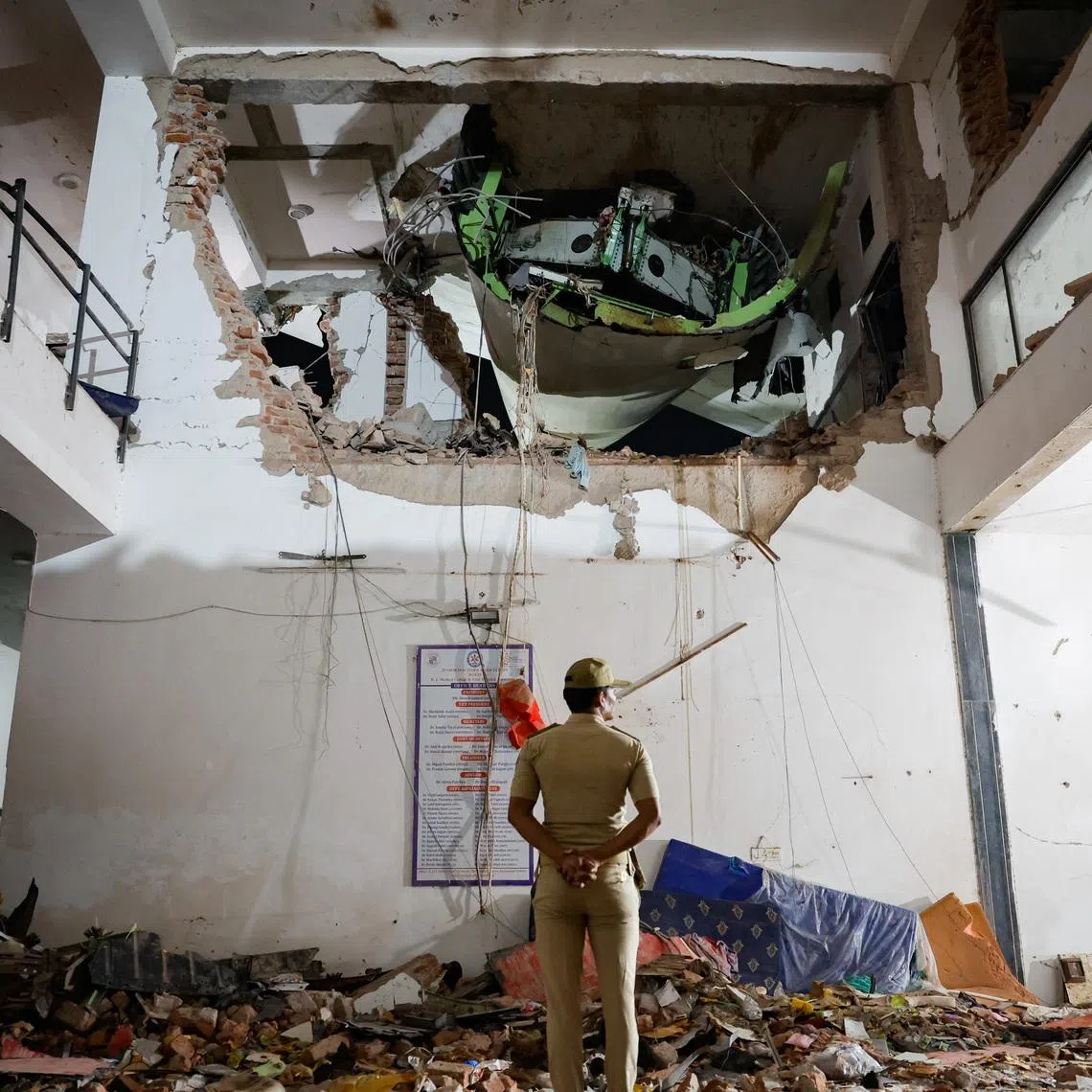 A police officer stands in front of the wreckage of an Air India aircraft which crashed during take-off from an airport in India on June 12, 2025.