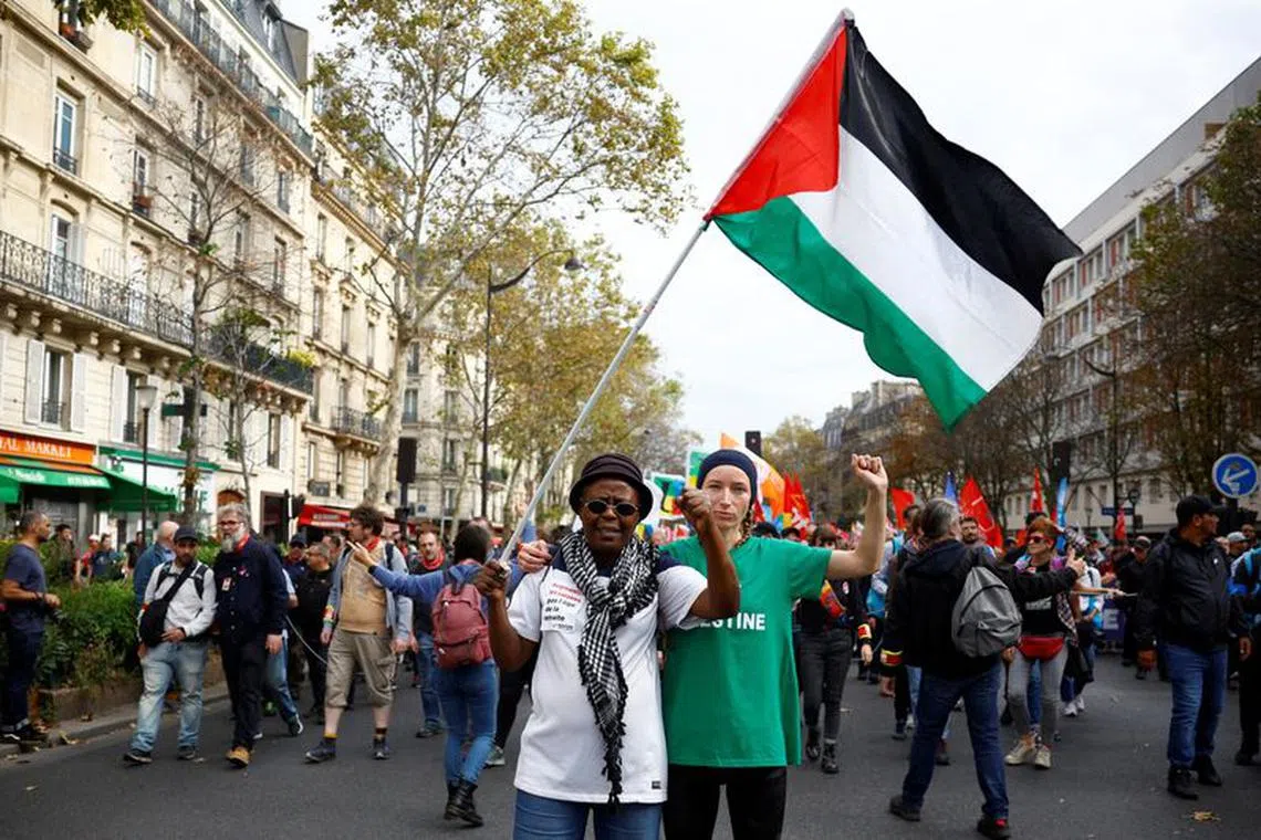 Protesters hold a Palestinian flag to protest the ban of pro-Palestinian demonstrations in France as part of the ongoing conflict between Israel and the Palestinian Islamist group Hamas, during a demonstration for more equality and higher wages and against austerity, in Paris, France, October 13, 2023. REUTERS/Sarah Meyssonnier/File Photo