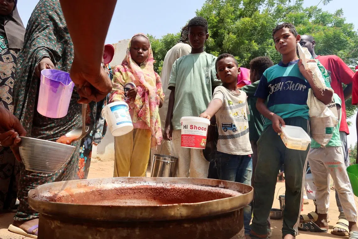 FILE PHOTO: People hold pots as volunteers distribute food in Omdurman, Sudan, September 3, 2023. REUTERS/El Tayeb Siddig/File Photo