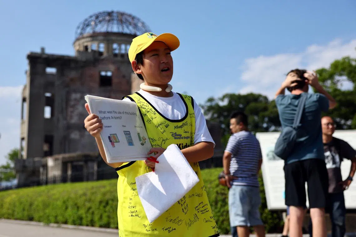 Shun Sasaki, 12, an elementary school student in Hiroshima, guides foreign visitors in English as a volunteer guide in front of the Atomic Bomb Dome in Hiroshima, western Japan July 15, 2025.   REUTERS/Issei Kato