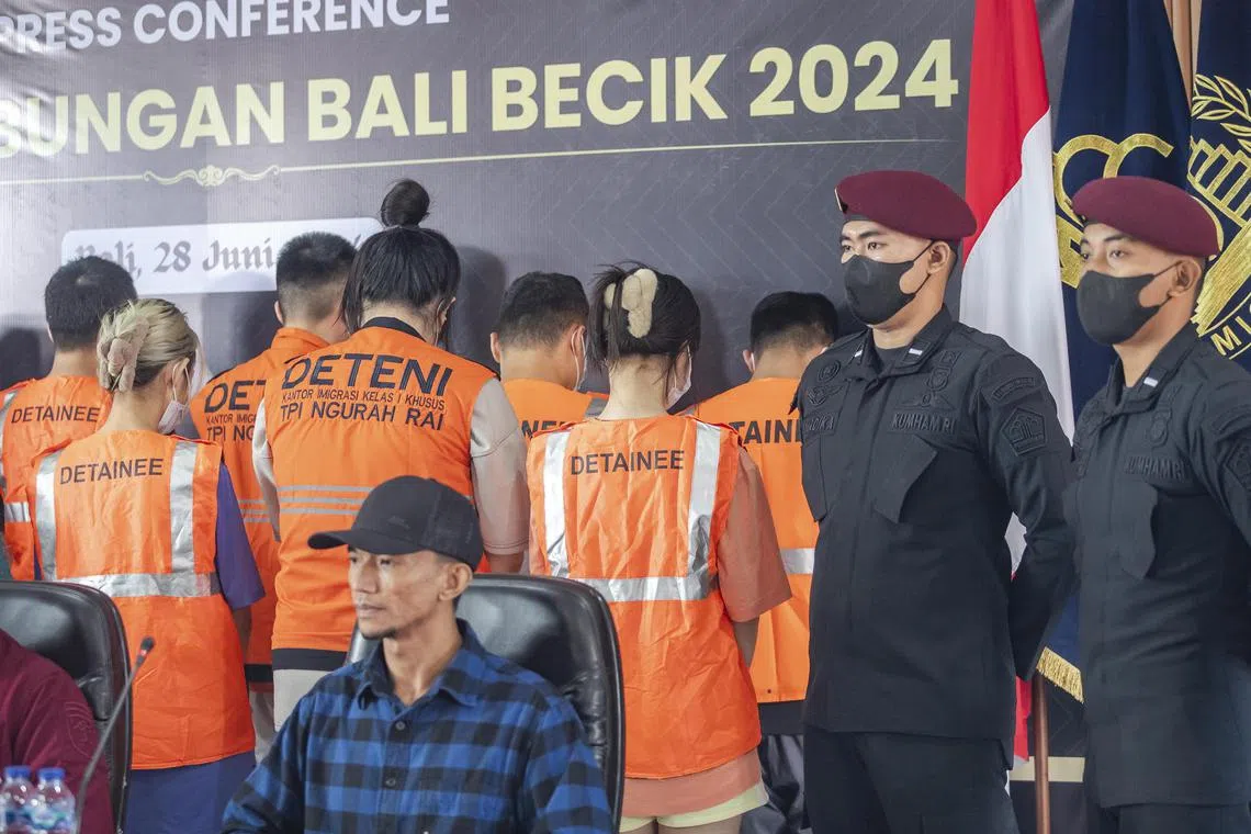 epa11442601 Indonesian authorities escort a group detained Taiwan nationals during a press conference at the Immigration Detention Center in Bali, Indonesia, 28 June 2024. A total of 103 Taiwanese nationals suspected of committing cybercrime were arrested by Indonesian immigration officers and police at a resort in Tabanan, Bali, on 26 June 2024.  EPA-EFE/MADE NAGI