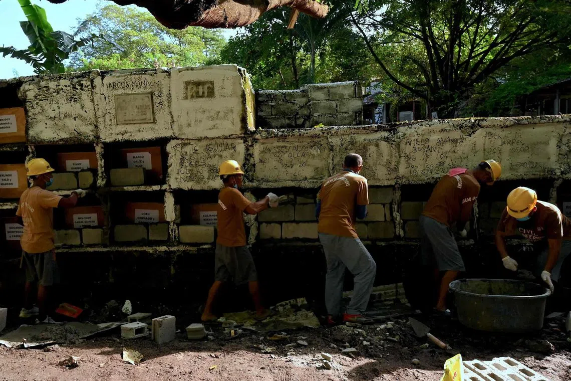 Prison inmates seal the tombs during a mass burial of 70 unclaimed bodies of prisoners at New Bilibid Prison Cemetery in Muntinlupa, metro Manila on December 2, 2022. 