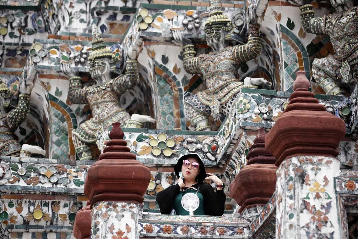 epa10645503 A foreign tourist uses a handheld electric fan to cool down from hot weather during a visit at Wat Arun or Temple of Dawn in Bangkok, Thailand, 22 May 2023. According to Deputy Government Spokesperson Traisulee Traisaranakul, 9.47 million foreign tourists visited Thailand since January 2023 generating about 391 billion Thai baht (11.36 billion US dollars or 10.50 billion euro) in revenue. Further growth is projected in Thailand's tourism industry with an expected increase of seven million Chinese tourists arrivals this year. EPA-EFE/RUNGROJ YONGRIT