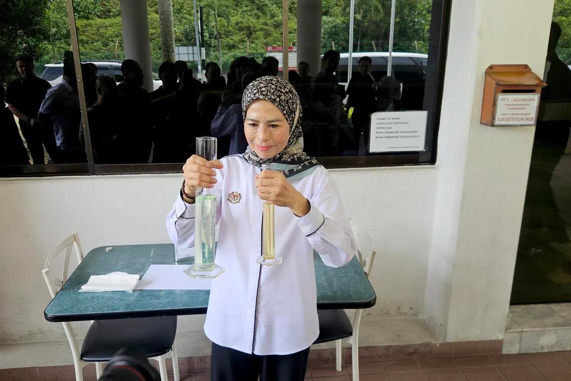 Plantation and Commodities Minister Noraini Ahmad holding a test tube containing pure B100 palm oil-based biodiesel (left) and a test tube containing B15 biodiesel (right).