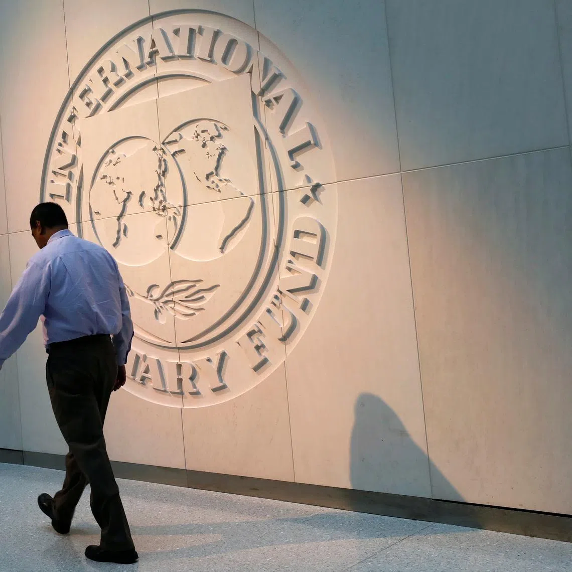 A man walks past the International Monetary Fund (IMF) logo at its headquarters in Washington, U.S., May 10, 2018. REUTERS/Yuri Gripas/File Photo
