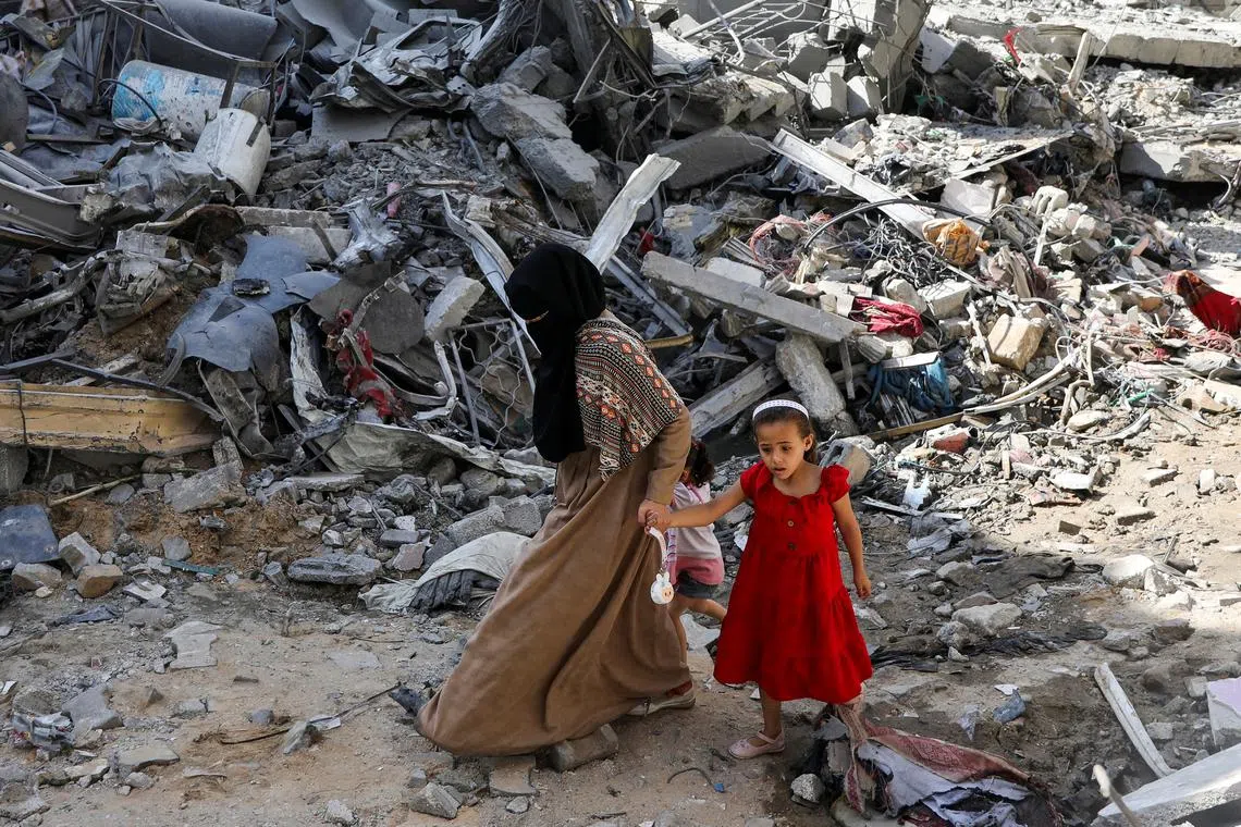 FILE PHOTO: A woman and child walk among debris, aftermath of Israeli strikes at the area, where Israeli hostages were rescued on Saturday, as Palestinian death toll rises to 274, amid the Israel-Hamas conflict, in Nuseirat refugee camp in the central Gaza Strip, June 9, 2024. REUTERS/Abed Khaled/File Photo