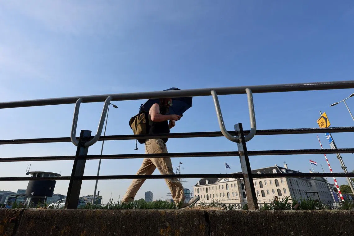 A man walks with an umbrella in Amsterdam, during the heatwave hitting the country, while a code red alert is issued, in Amsterdam, the Netherlands, June 26, 2026. REUTERS/Nicolas Economou