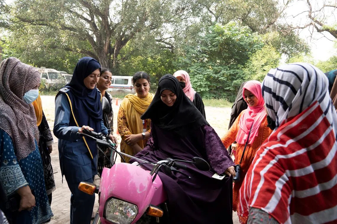 Humaira Rafaqat, a senior traffic warden, teaches women how to ride a bike while wearing an abaya, during a training session as part of the \"Women on Wheels\" program organised by the traffic police department in Lahore, Pakistan, October 1, 2024. REUTERS/Nida Mehboob