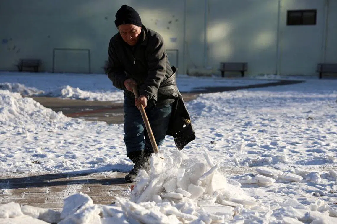 A worker clears snow at a park during winter solstice in Beijing, China December 22, 2023. REUTERS/Florence Lo/File Photo