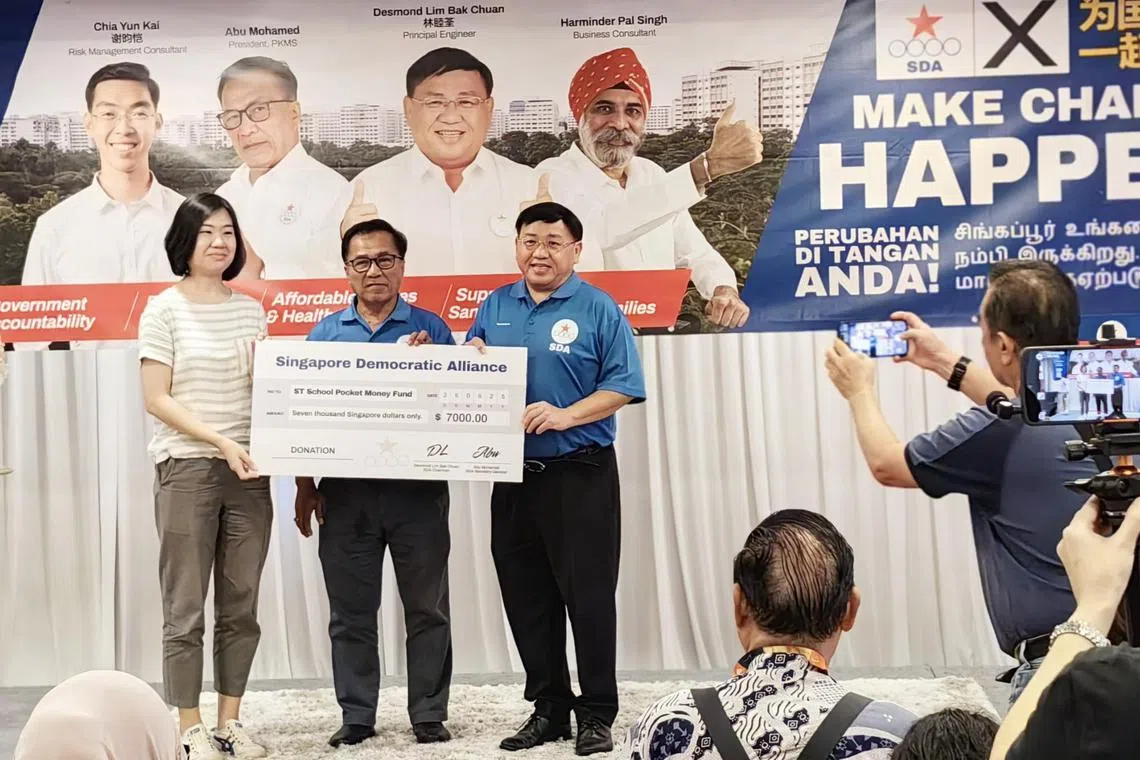 SDA chairman Desmond Lim (at right) and secretary-general Abu Mohamed handing over the initial amount raised to STSPMF general manager Lau Hui Ling on May 25.