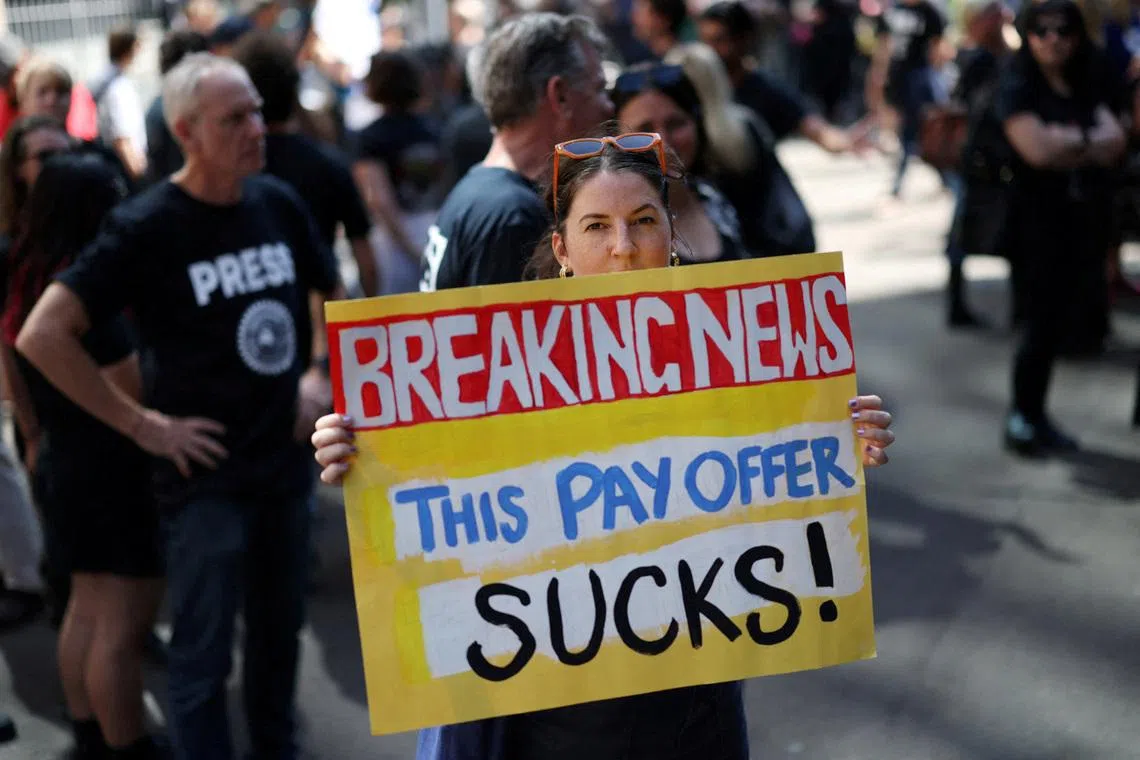 A woman holds a placard as ABC staff and journalists strike outside the national broadcaster's headquarters in Sydney, Australia, March 25, 2026. REUTERS/Hollie Adams