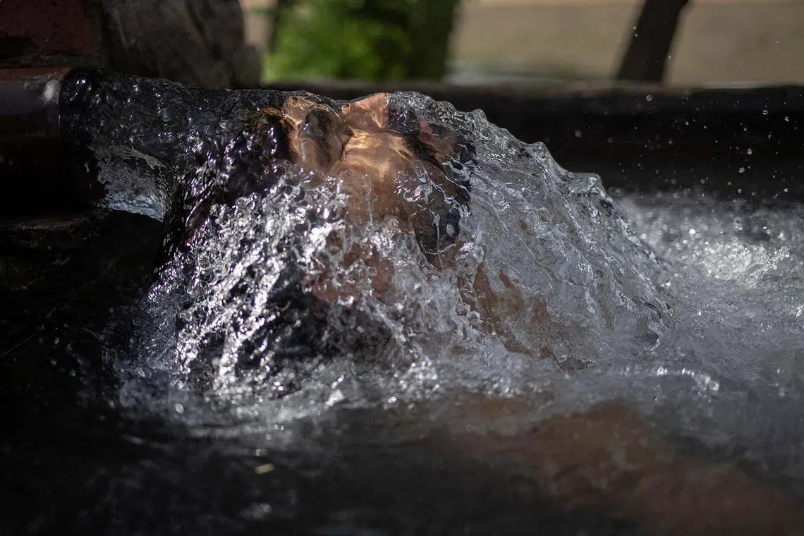 Faisal, 18, a truck driver, cooling off in groundwater being pumped to irrigate nearby fields as temperatures soared above 48 deg C during a heatwave in Daska, Pakistan, June 10, 2025. 