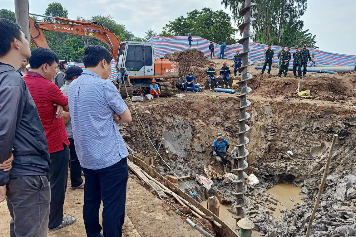 Rescuers look down into the site of where a 10-year-old boy has been trapped in a 35-metre-deep shaft at a bridge construction area in Vietnam's Dong Thap province on Jan 2, 2023. 