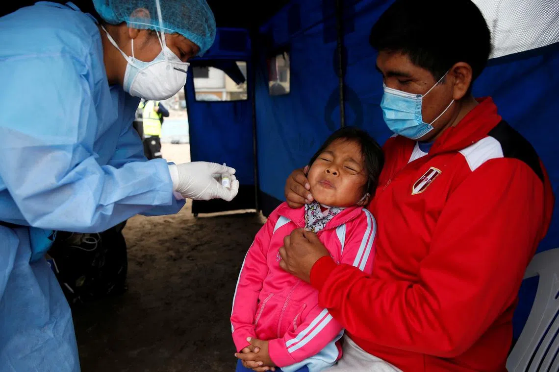 A little girl reacts after receiving an oral vaccine during a vaccination drive for diphtheria, influenza, tetanus and pneumococcus in Lima, Peru November 7, 2020. REUTERS/Sebastian Castaneda/File Photo