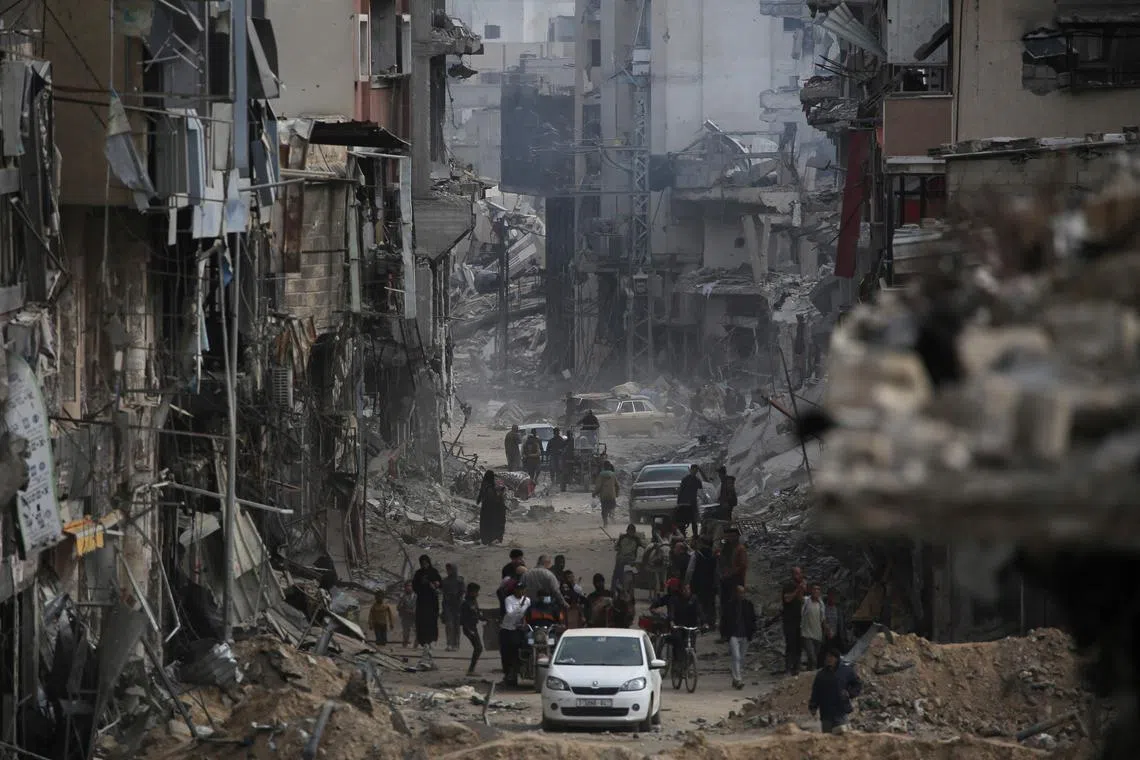 Palestinians walk past damaged buildings in Khan Yunis on after Israel pulled its ground forces out.