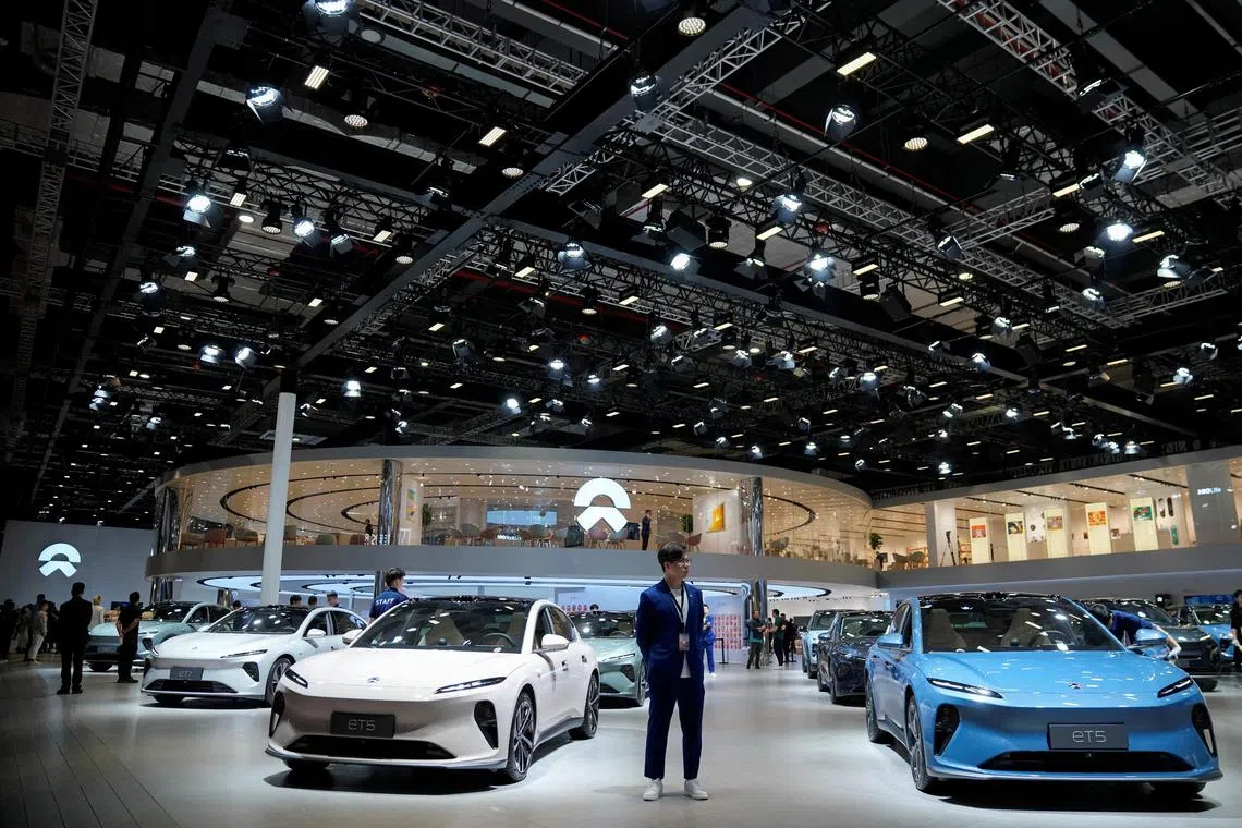 A staff member stands near Nio ET5 cars at its booth at the Auto Shanghai show, in Shanghai, China, April 18, 2023. REUTERS/Aly Song/File Photo