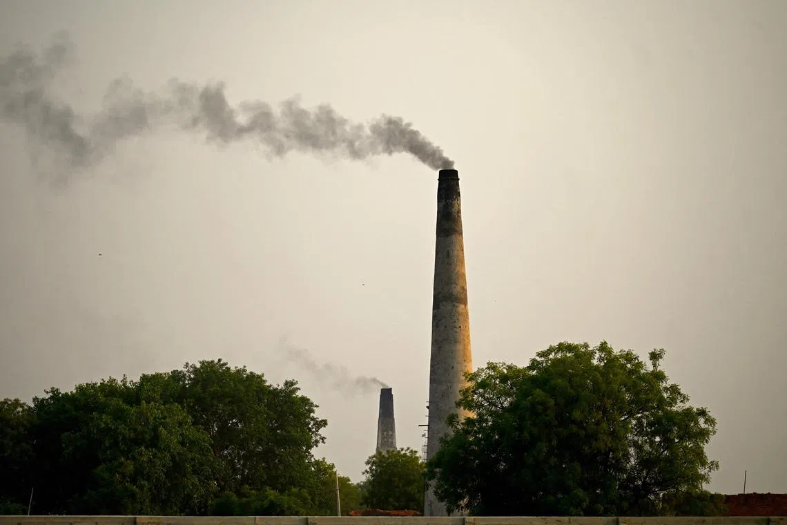 In this picture taken on May 5, 2023, smoke spouts of a chimney of a brick kiln on the outskirts of Faridabad. (Photo by Money SHARMA / AFP)