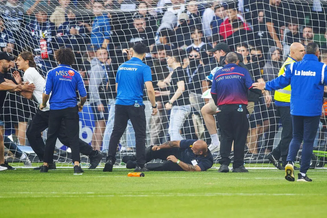 Security personnel trying to stop Melbourne Victory fans from invading the pitch during the Australian A-League men's football match between Melbourne City and the Melbourne Victory at AAMI Park in Melbourne, Australia, on Saturday (Dec 17, 2022). 