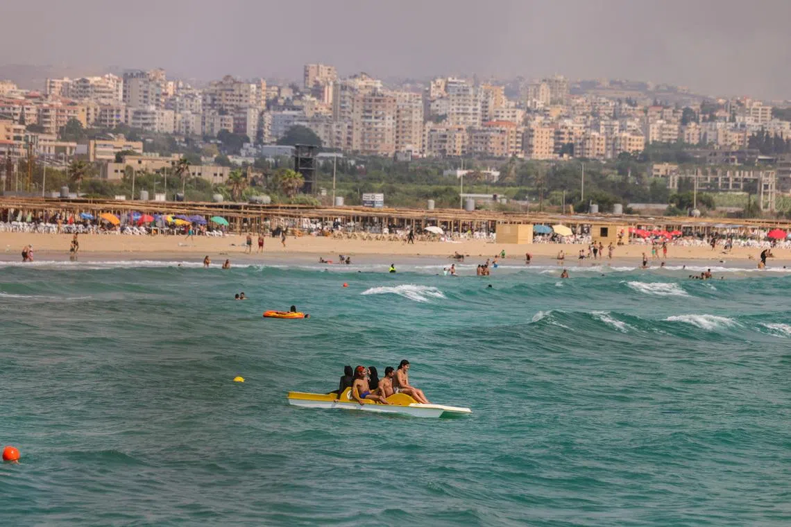 People who returned home following displacement during the war, after the Israel-Lebanon deal, relax on the beach and in the water in Tyre, southern Lebanon, July 5, 2026. REUTERS/Zohra Bensemra