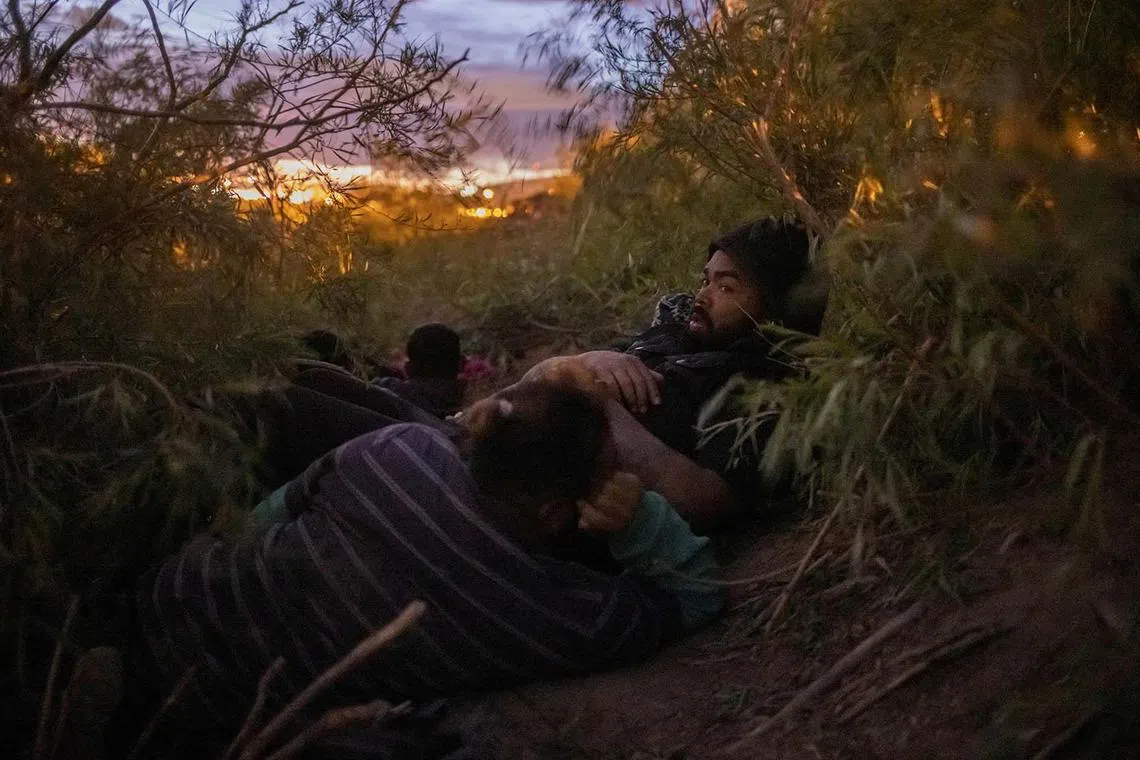 Migrants from South and Central America hiding from the National Guard patrolling a razor wire fence along the bank of the Rio Grande river in El Paso, Texas, US, March 26, 2024. 