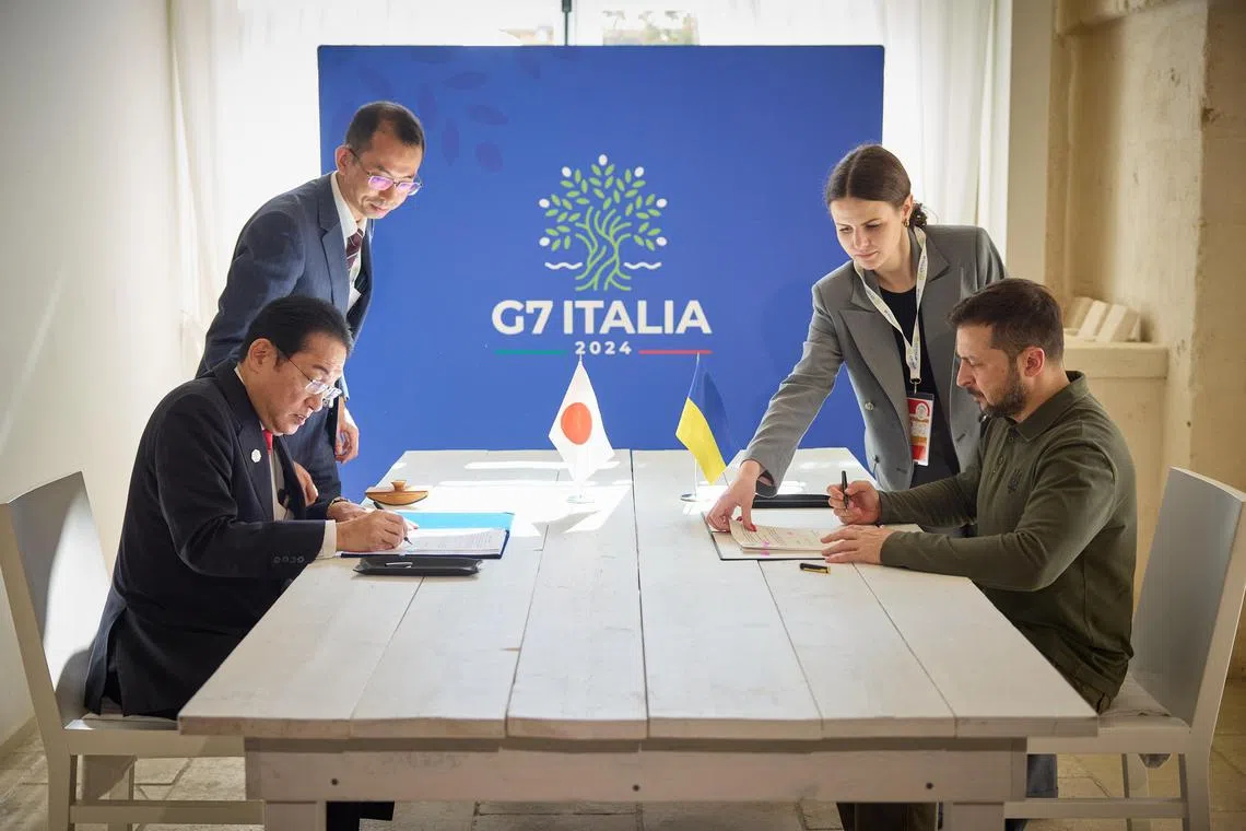 Japan's Prime Minister Fumio Kishida (left) and Ukrainian President Volodymyr Zelensky signing a bilateral accord on the sidelines of the G-7 meeting. 
