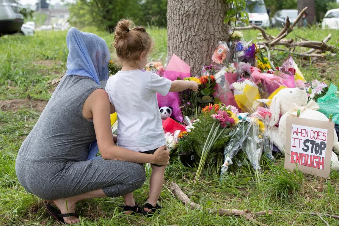 A 2021 photo shows people paying their respects at a makeshift memorial for a family mown down by a truck driver while they were out for an evening walk.