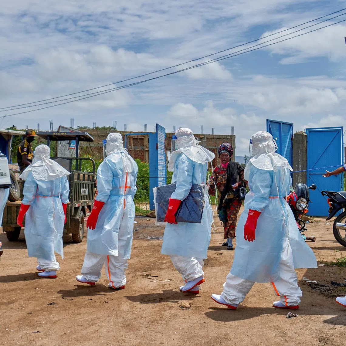People react while Red Cross workers walk in a formation as they disinfect Rwampara general hospital before handling the body of a person who died of Ebola, as aid agencies intensify efforts to contain a new Ebola outbreak involving the Bundibugyo strain, in Rwampara outside Bunia, Ituri province, Democratic Republic of Congo, May 21, 2026. REUTERS/Gradel Muyisa Mumbere