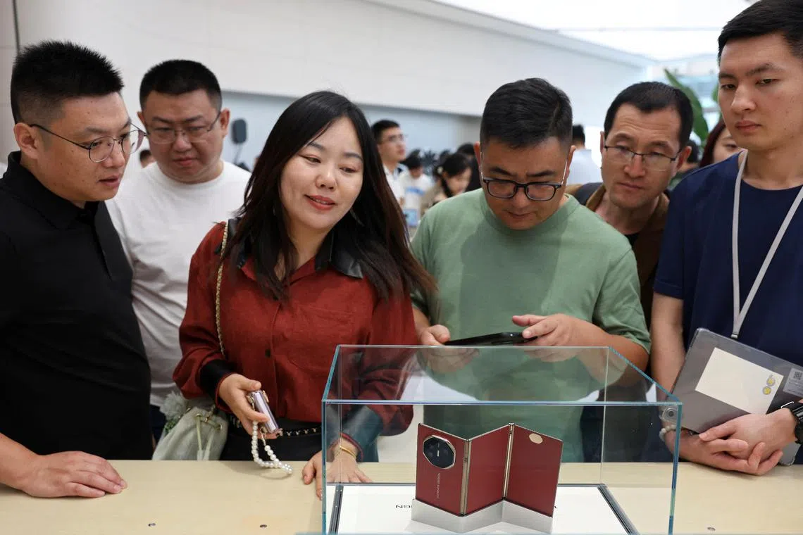 People look at Huawei's new tri-foldable smartphone Mate XT at a Huawei flagship store in Beijing on September 10, 2024. 