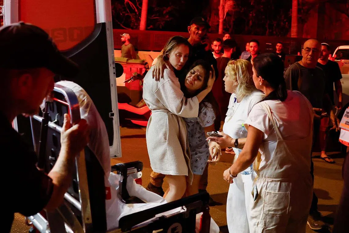A woman is embraced near an impact site while she prepares to get into an ambulance, amid hostilities between Hezbollah and Israeli forces, in Nahariya, Israel, Nov 12, 2024.