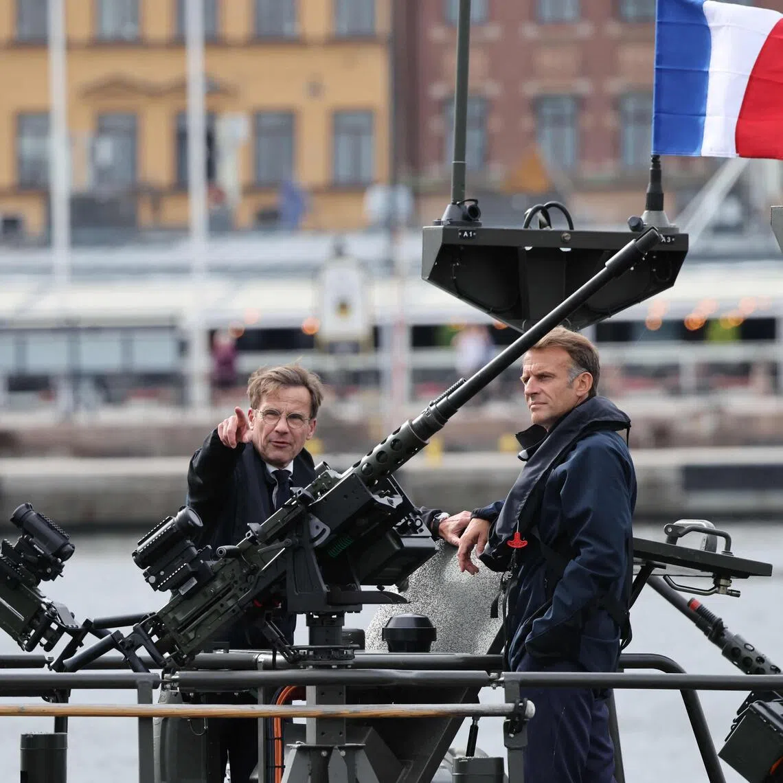 French President Emmanuel Macron (right) and Swedish Prime Minister Ulf Kristersson standing aboard a Swedish Navy CB90 fast assault craft in Stockholm, Sweden, on Aug 31.