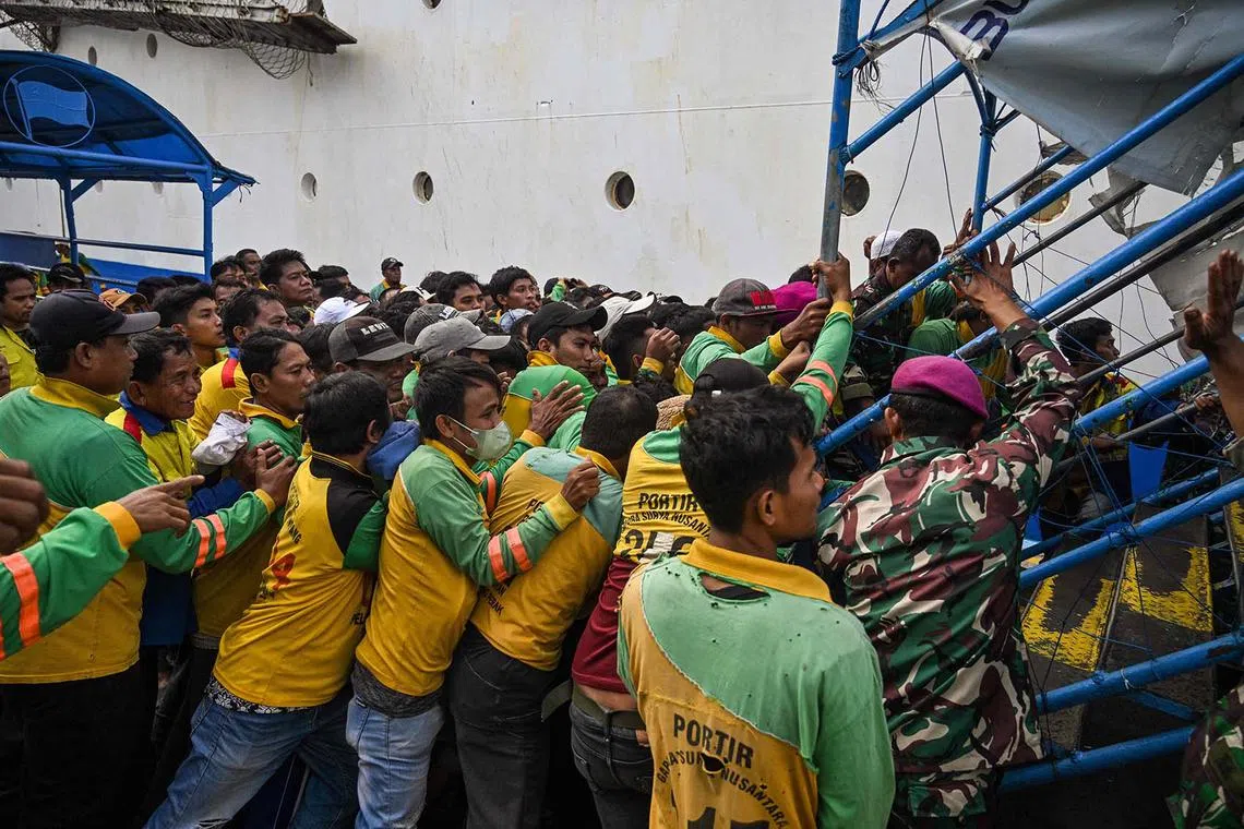 Porters scrambling to board a passenger ship at the Perak seaport in Surabaya on March 25, 2025, as people travel to their hometowns ahead of Eid al-Fitr which marks the end of the Muslim holy fasting month of Ramadan.