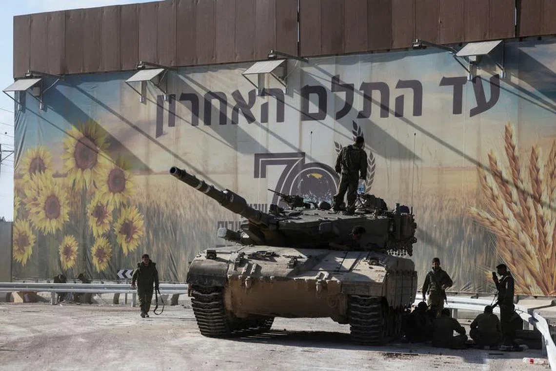 FILE PHOTO: Israeli soldiers gather on and around a tank near Israel's border with the Gaza Strip, in southern Israel October 15, 2023. REUTERS/Ronen Zvulun/File Photo