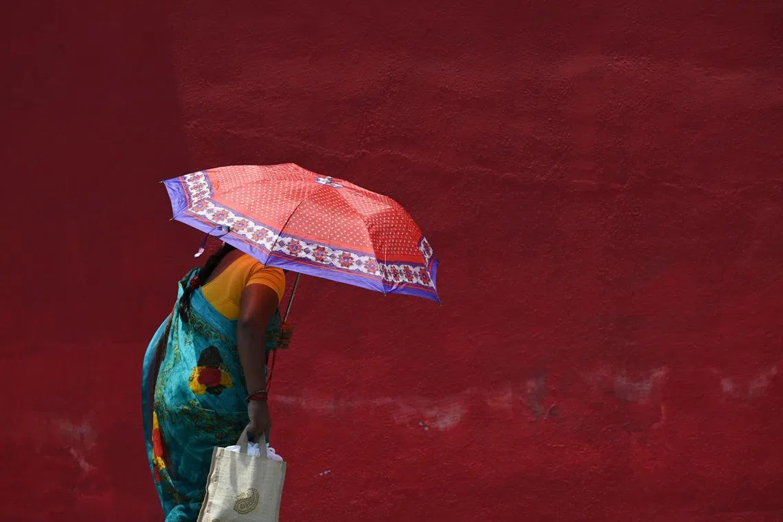(FILES) In this file photo taken on May 16, 2023, a woman shelters from the sun with an umbrella during a hot summer day in Chennai. Climate change made record-breaking deadly heatwaves in Bangladesh, India, Laos and Thailand last month at least 30 times more likely, according to a study published on May 17. (Photo by R. Satish BABU / AFP)