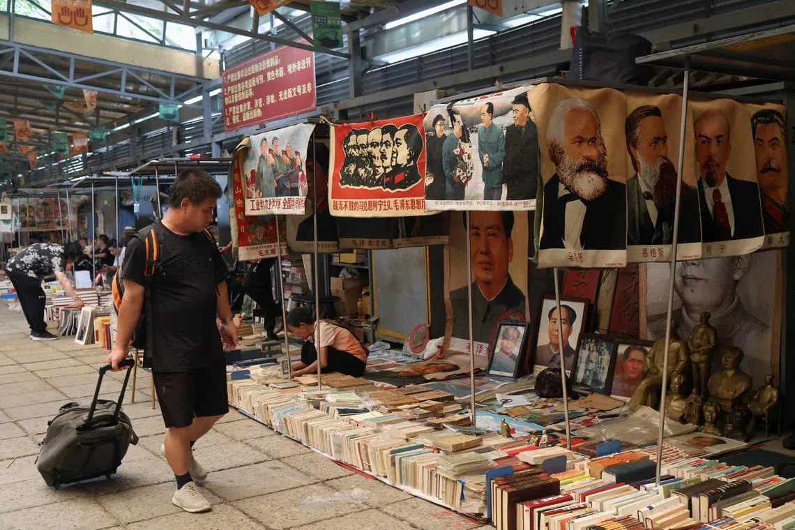 FILE PHOTO: A man walks past a sign warning against the sale of illegal publications,  underneath which secondhand books as well as images and statues of late Chinese chairman Mao Zedong and other leaders are displayed for sale at the Panjiayuan antique market in Beijing, China August 3, 2024. REUTERS/Florence Lo/File photo