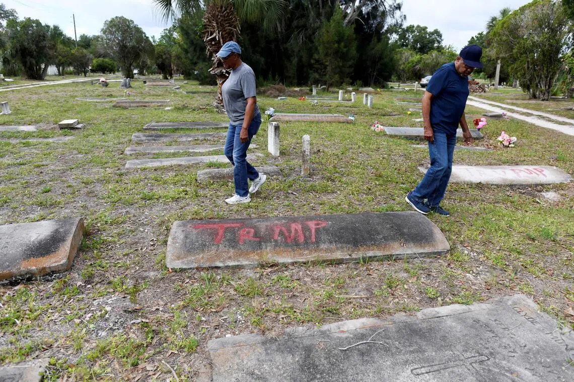 Family members of those buried at the Old Memphis Cemetery, a predominantly African-American cemetery in Palmetto, Florida, walking near a tomb with the word "Trump" spray-painted on it on May 14.