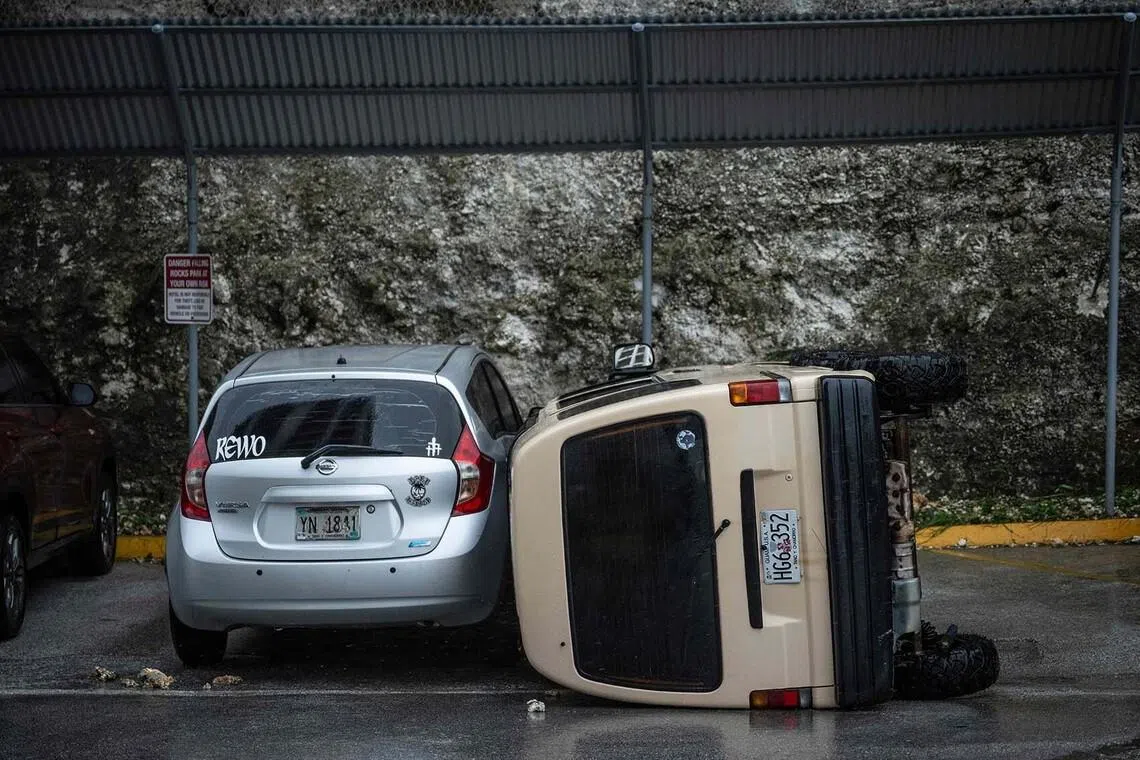 TOPSHOT - A car lies overturned after being flipped by strong winds brought by Super Typhoon Bavi in Guam on July 6, 2026. A "super typhoon" with the force of a category-five hurricane tore through the US Pacific territories of Northern Marianas and Guam on July 6, with authorities saying they had received reports of "major" damage on the small island of Rota. (Photo by Yuichi YAMAZAKI / AFP)