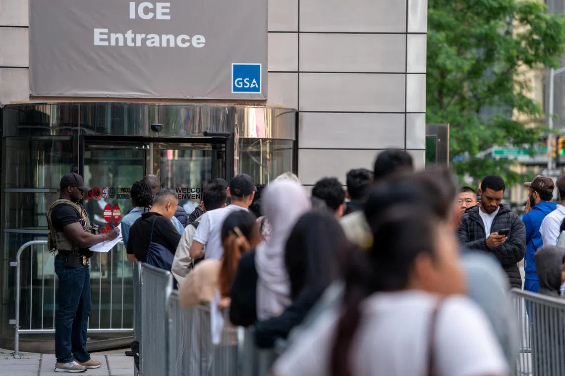 FILE PHOTO: An ICE agent speaks to people lined up to enter the U.S. Immigration Court, in Manhattan, New York City, U.S., June 5, 2025. REUTERS/David 'Dee' Delgado/ File Photo