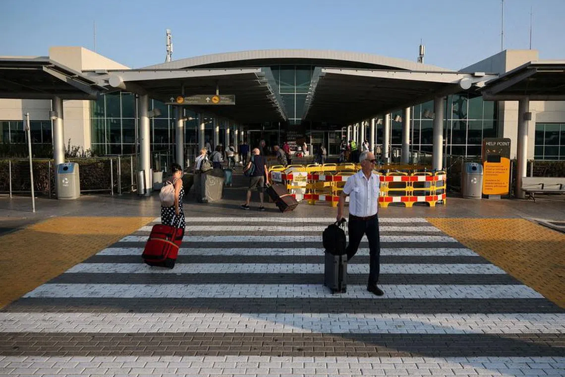 FILE PHOTO: People walk with their luggage outside Larnaca International airport, in Larnaca, Cyprus, October 9, 2023. REUTERS/Yiannis Kourtoglou/File Photo