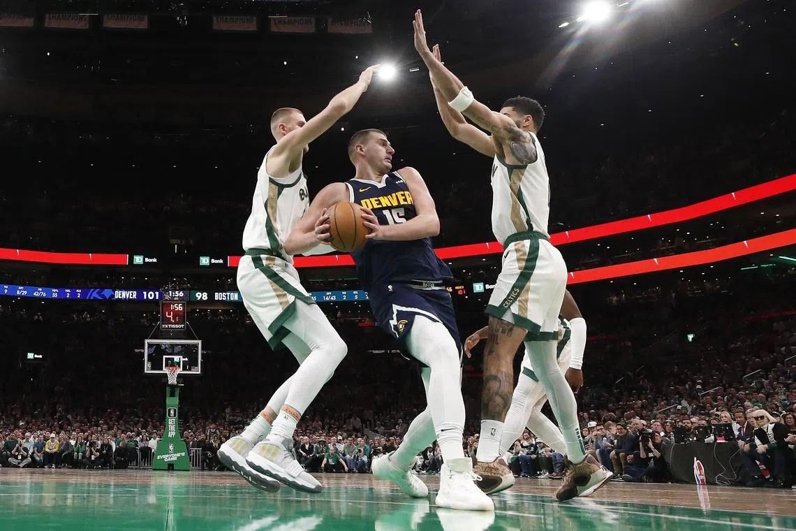 Nikola Jokic of the Denver Nuggets looks for a way past the Boston Celtics' Kristaps Porzingis and Jayson Tatum during the second half at TD Garden.