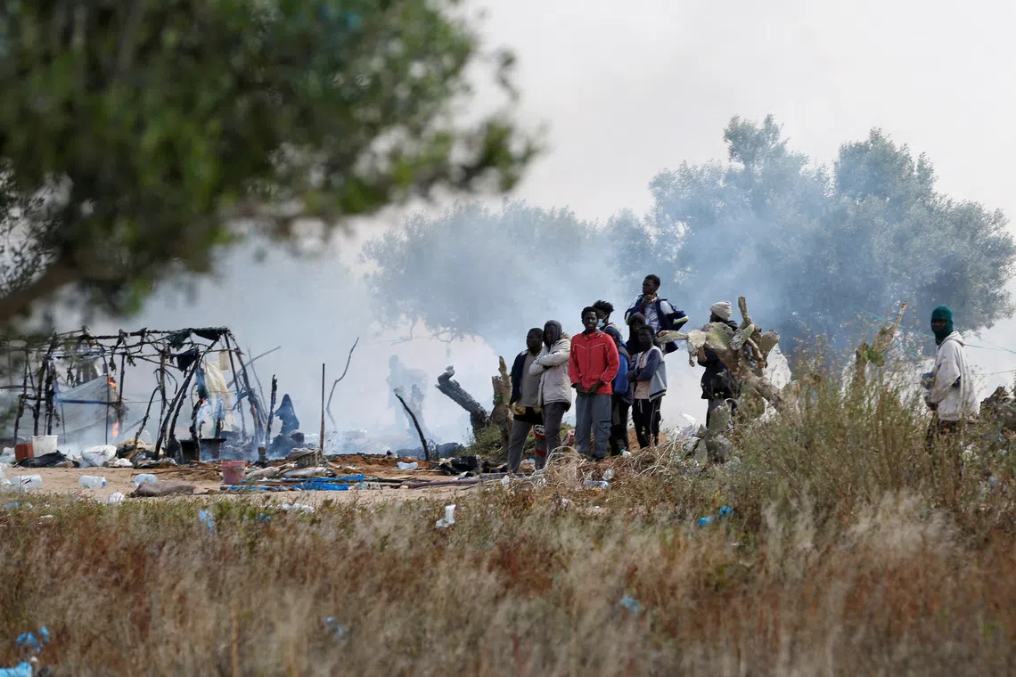 FILE PHOTO: Migrants gather near burnt tents, as Tunisian authorities have dismantled makeshift camps housing sub-Saharan African migrants, in Amra, Sfax, Tunisia April 24, 2025. REUTERS/Zoubeir Souissi/File Photo