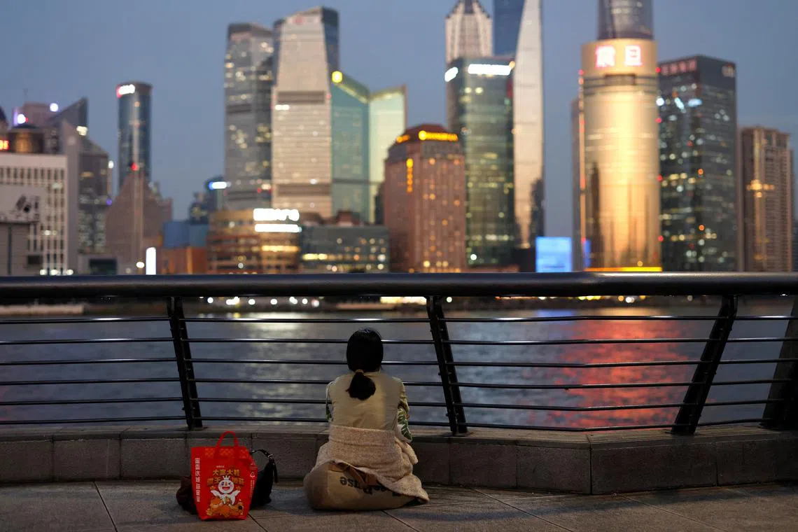 FILE PHOTO: A woman sits on the Bund near Huangpu river as she looks on the financial district of Pudong in Shanghai, China September 27, 2024. REUTERS/Tingshu Wang/File Photo